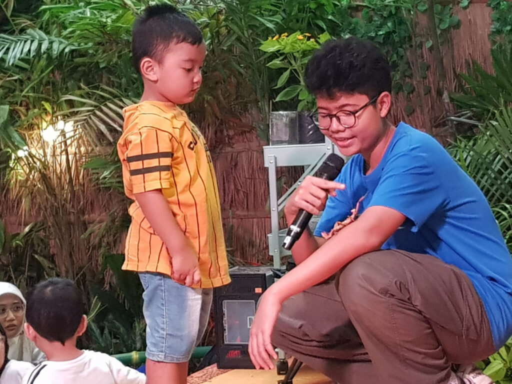 Foto Caption : Nadhif sedang mengenalkan serangga kepada seorang anak di Explore The Jungle